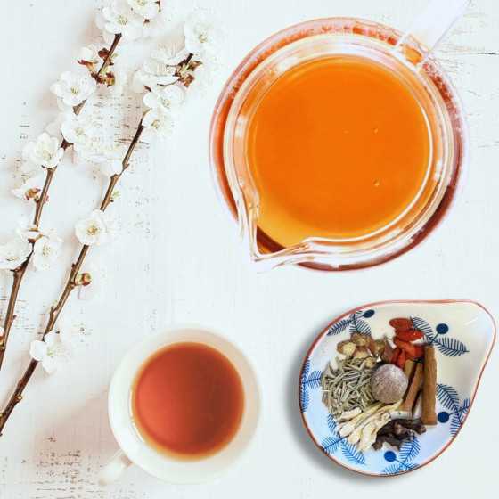 Tisane Le Montagnard dans une théière et une tasse, avec des épices disposées à côté, sans lait