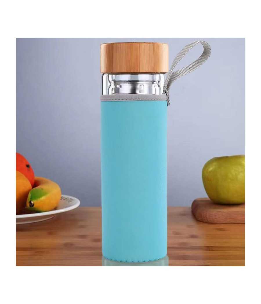 Bouteille infuseur en verre avec housse bleue et bouchon aspect bois, posée sur une table