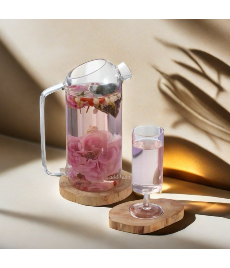 Théière transparente remplie d’une infusion rose fleurie, accompagnée d’un verre