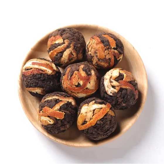 Boules de thé noir aux écorces d’orange dans une coupelle en bois